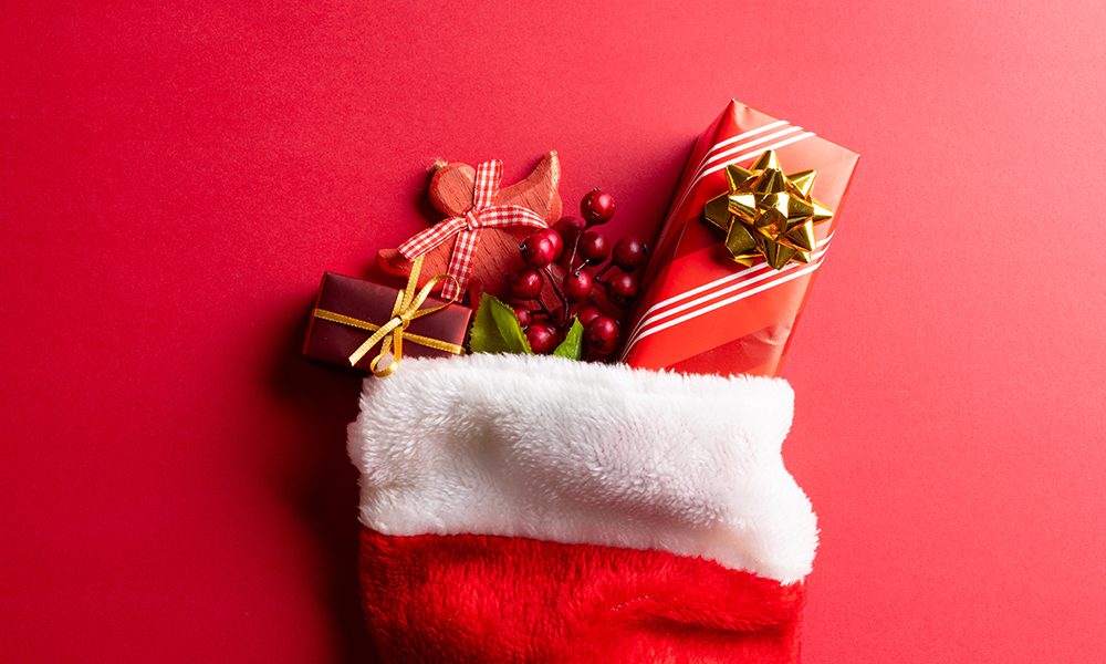 Image of christmas gifts in christmas stocking and copy space on